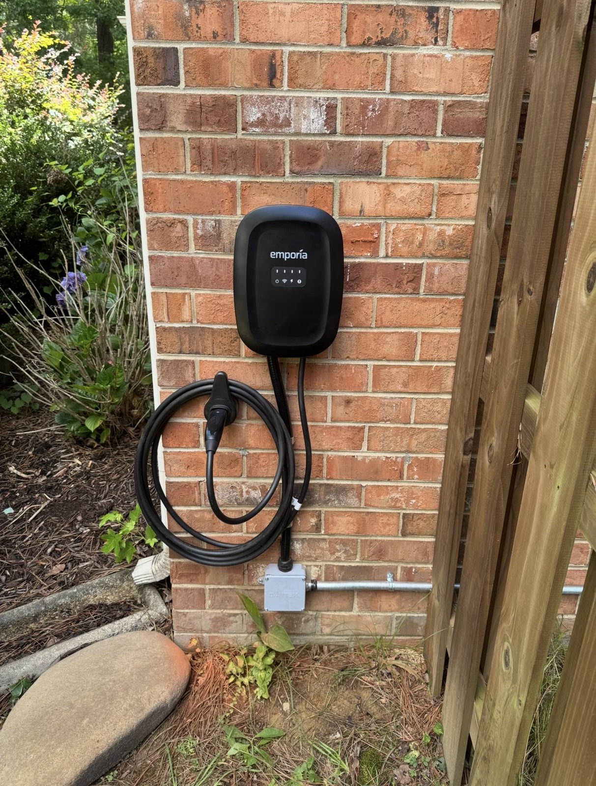 Level 2 home EV charger installed by GreenKey on a brick home exterior